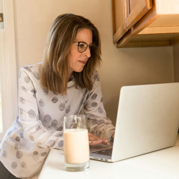 Woman with glass of milk and laptop