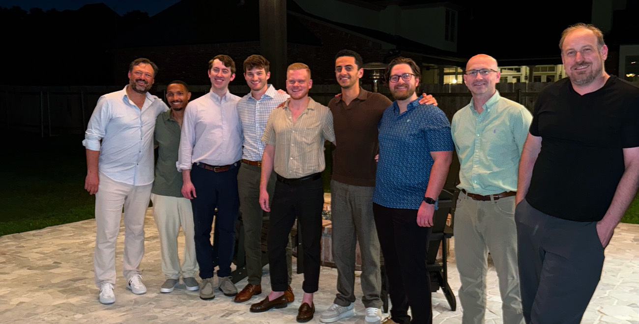Group of Ochsner general surgery housestaff and residents posing together on a stone patio at night.