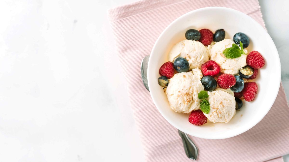 Scoops of vanilla ice cream in a bowl with berries