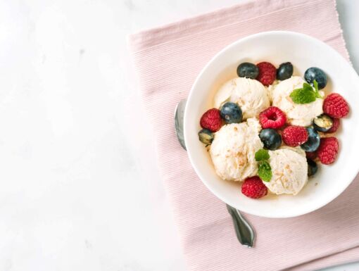 Scoops of vanilla ice cream in a bowl with berries