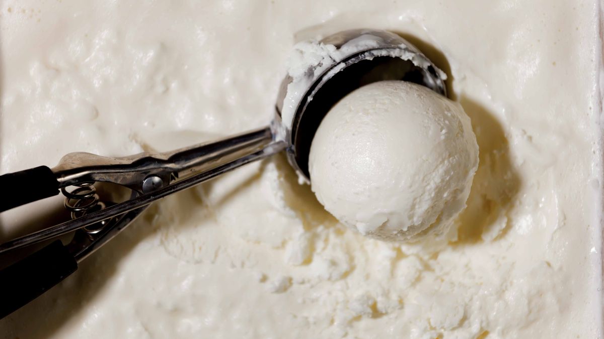 Ice cream scoop in container of vanilla ice cream