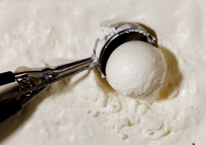 Ice cream scoop in container of vanilla ice cream