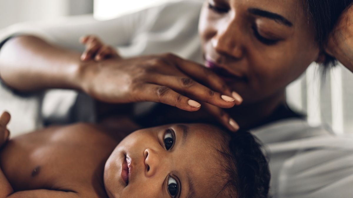 Black mother playing with baby on blanket