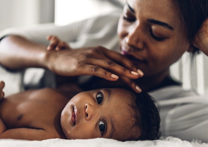Black mother playing with baby on blanket