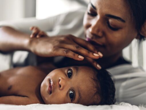 Black mother playing with baby on blanket