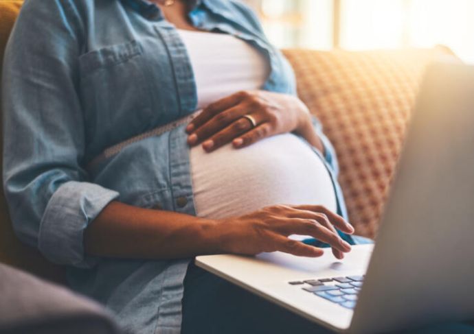 Pregnant woman on computer virtual classes mom