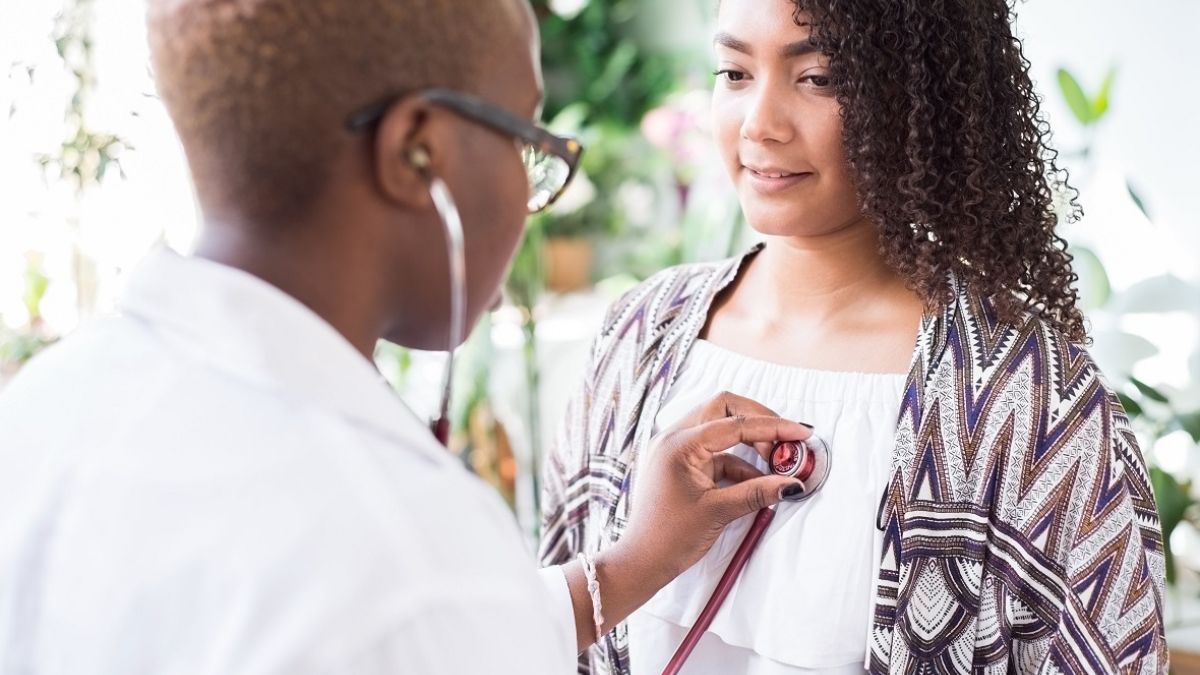 Black female doctor using a stethoscope to conduct exam for a patient