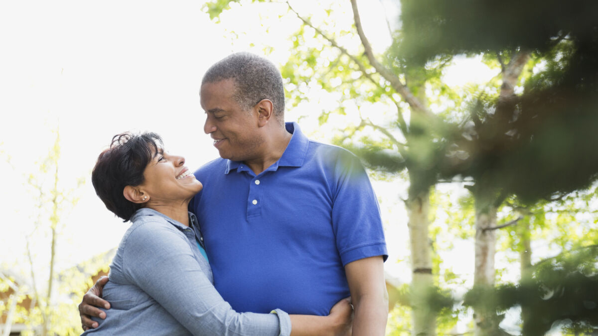Husband and wife smiling at each other outside on a walk