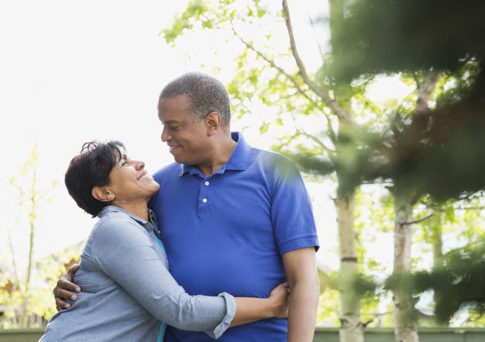 Husband and wife smiling at each other outside on a walk
