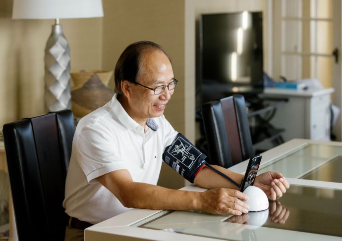 Man taking blood pressure at home with digital cuff