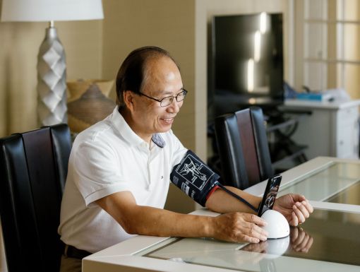 Man taking blood pressure at home with digital cuff