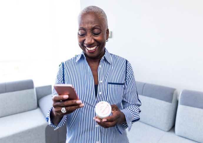 Smiling woman with a phone and pills in her hands