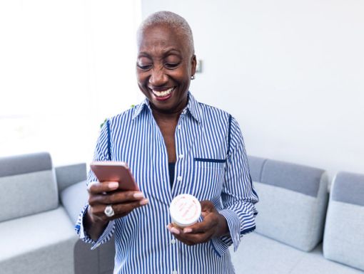 Smiling woman with a phone and pills in her hands