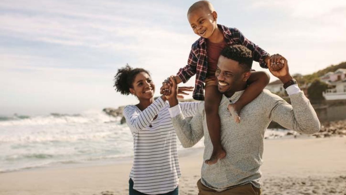 A mom, dad and son laughing on the beach