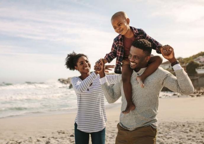 A mom, dad and son laughing on the beach