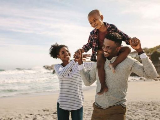 A mom, dad and son laughing on the beach