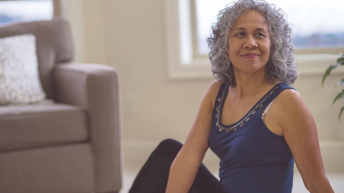 Woman in a sitting stretch on living room floor for gut health