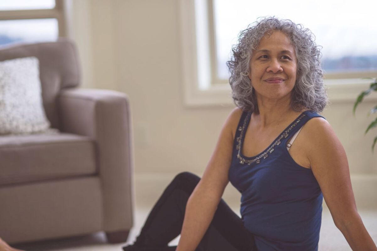 Woman in a sitting stretch on living room floor for gut health