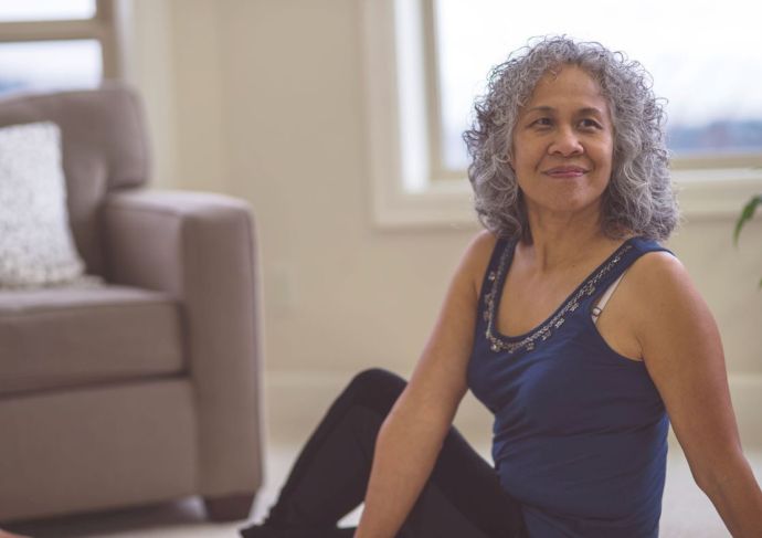 Woman in a sitting stretch on living room floor for gut health