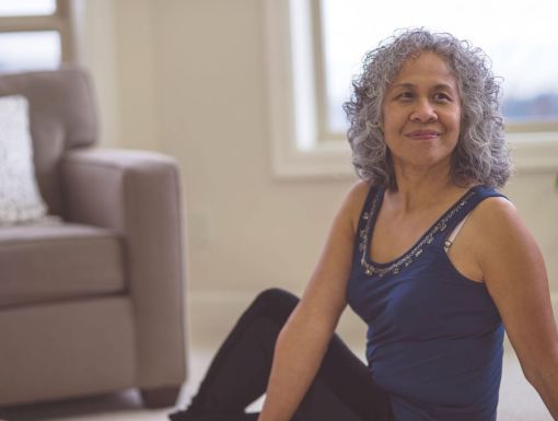 Woman in a sitting stretch on living room floor for gut health