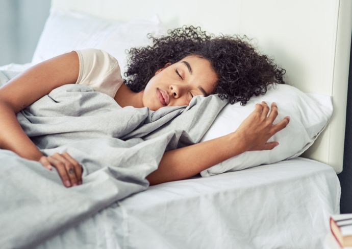 A woman sleeping in a bed with a blanket over her