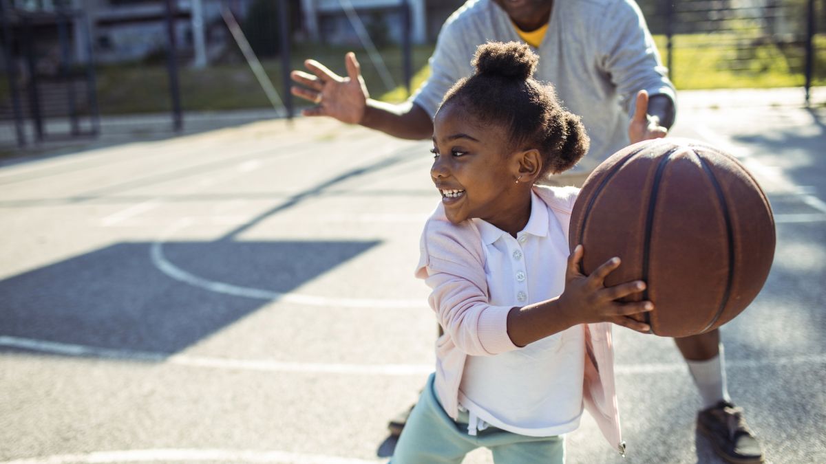 Little girl child playing basketball with father