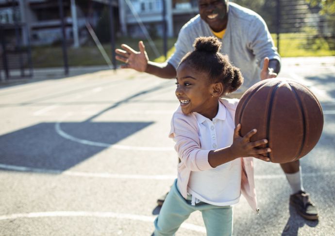 Little girl child playing basketball with father