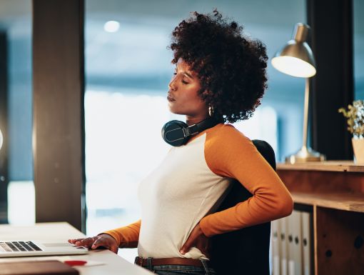 Woman at desk holding lower back
