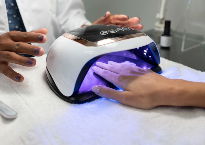 Woman getting a gel manicure and drying the nail polish with a UV lamp