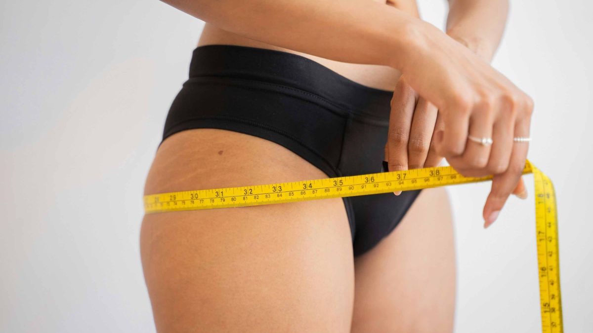 Woman putting tape measure around hips