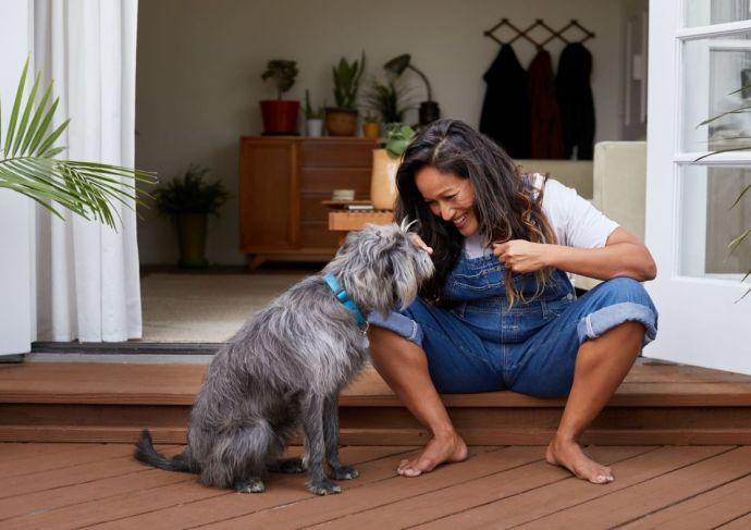 Woman sitting on back porch engaging with dog