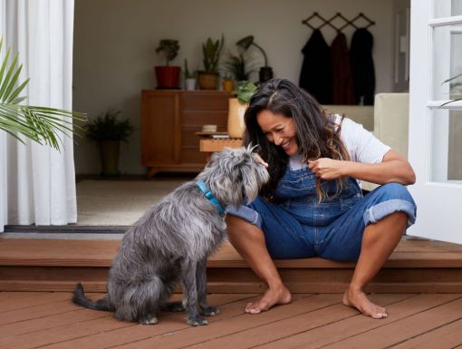 Woman sitting on back porch engaging with dog
