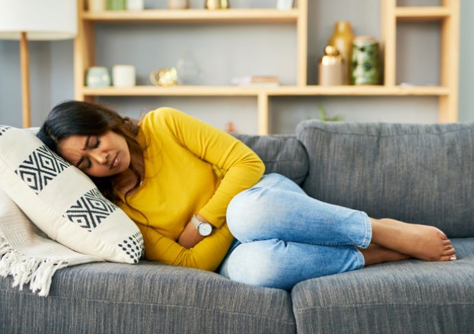 Woman laying on couch holding her stomach