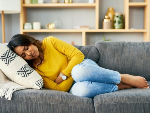 Woman laying on couch holding her stomach