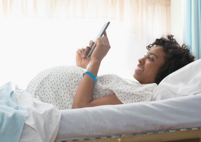 Prgnant women laying in hospital bed smiling