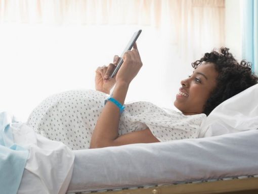 Prgnant women laying in hospital bed smiling