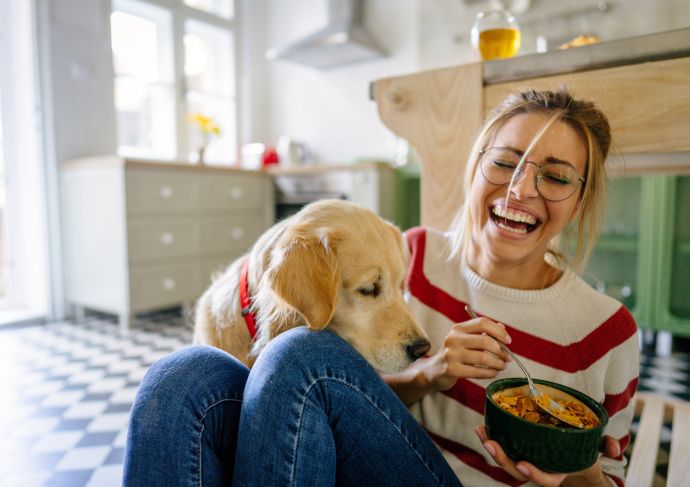 Girl eating cereal with dog