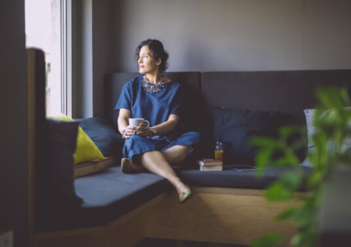 Woman sitting in her house, staring off into the distance thinking