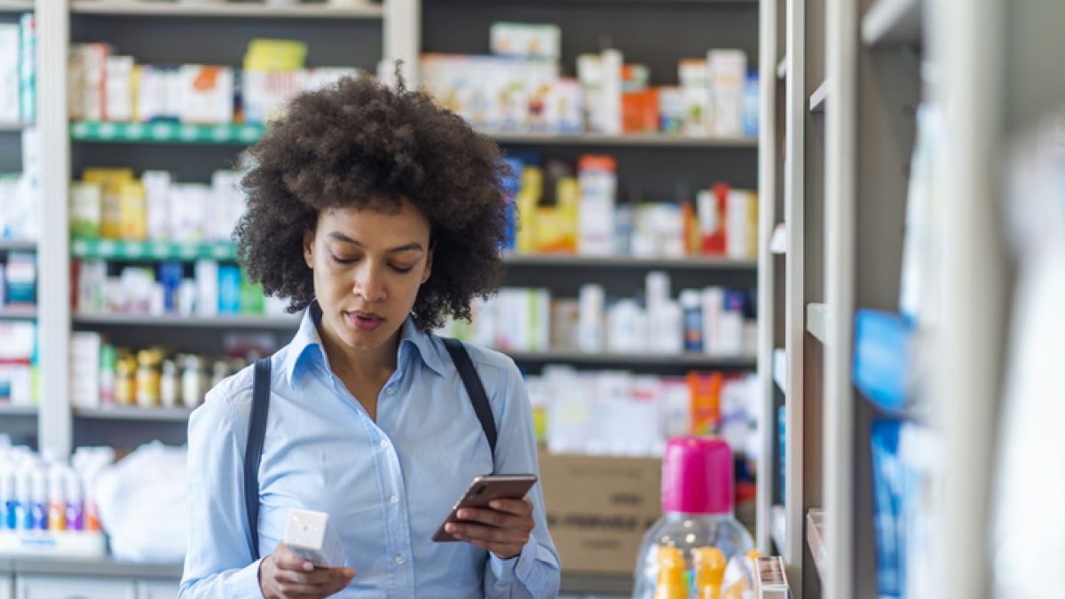 Woman looking at the ingredients on the back of a medicine box
