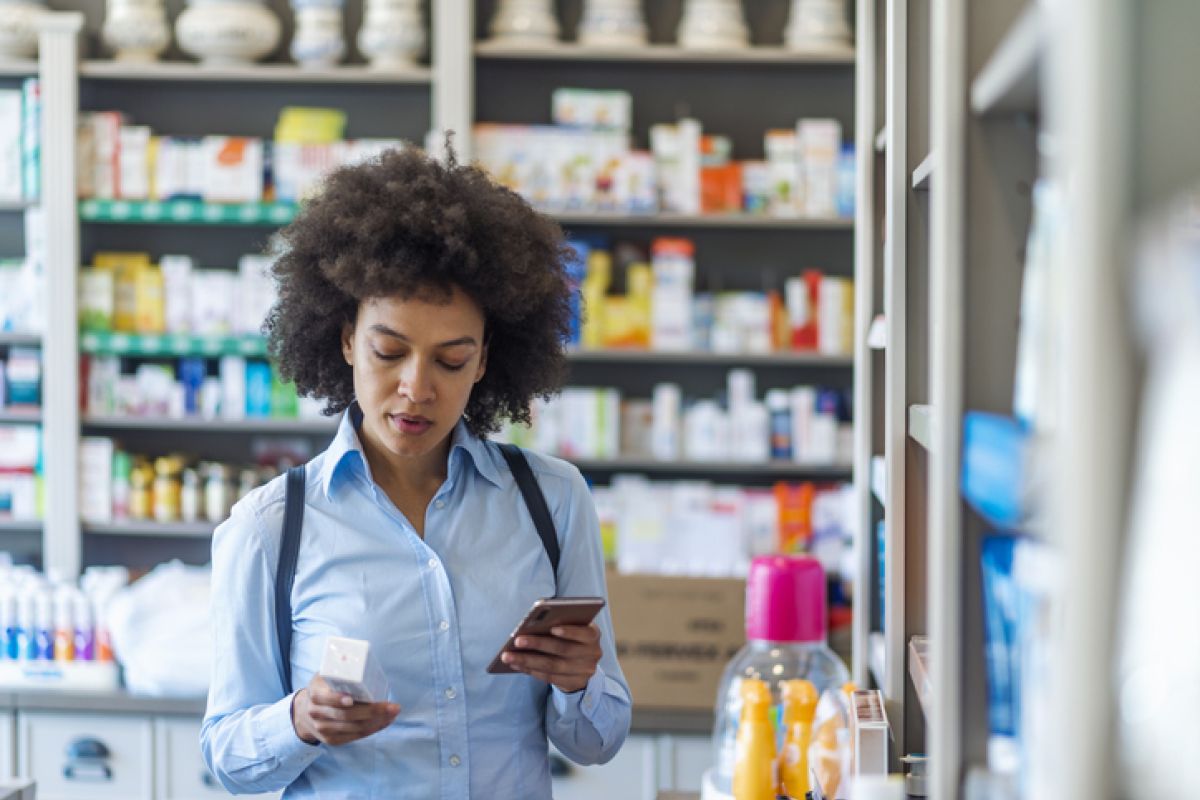 Woman looking at the ingredients on the back of a medicine box