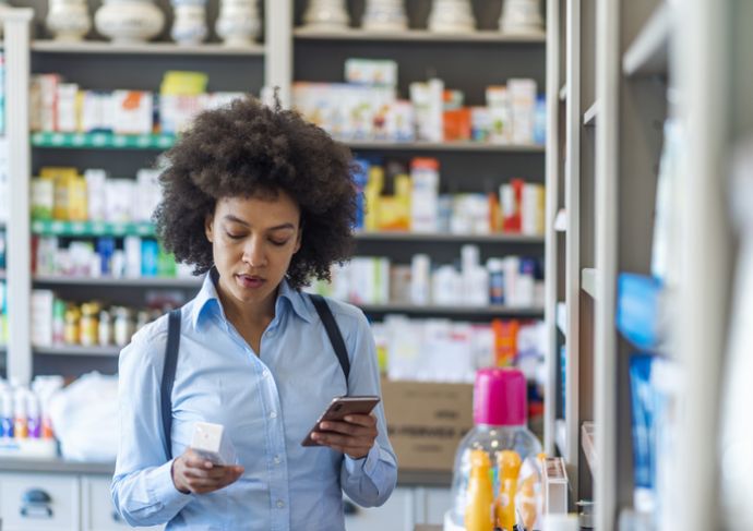 Woman looking at the ingredients on the back of a medicine box