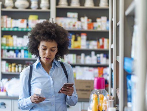 Woman looking at the ingredients on the back of a medicine box