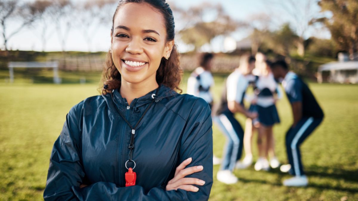 Cheerleading coach smiling with her team in the background