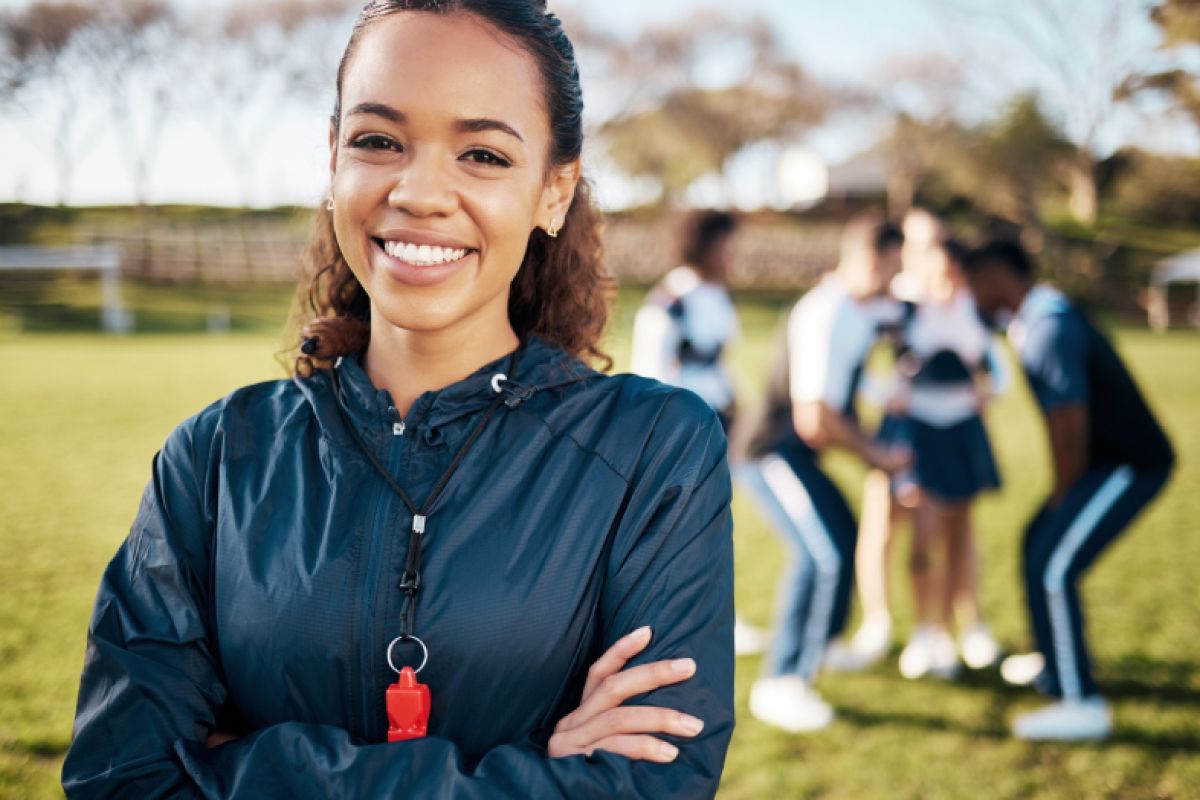 Cheerleading coach smiling with her team in the background