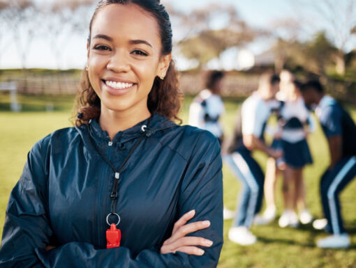 Cheerleading coach smiling with her team in the background