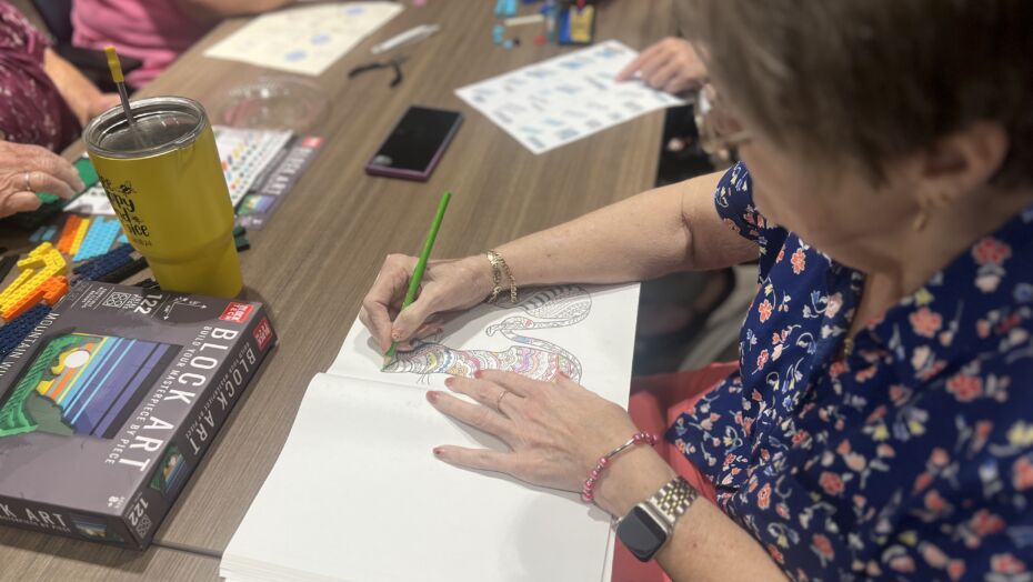 Woman coloring in coloring book at a table