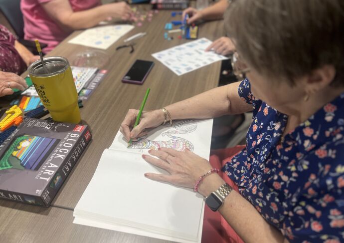 Woman coloring in coloring book at a table