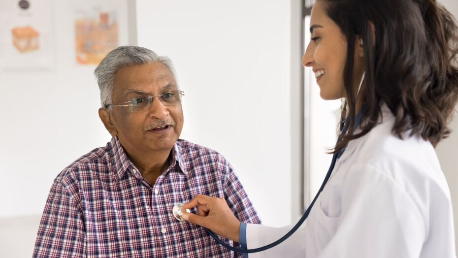 Female cardiologist holding stethoscope on older mans chest