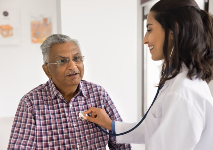 Female cardiologist holding stethoscope on older mans chest