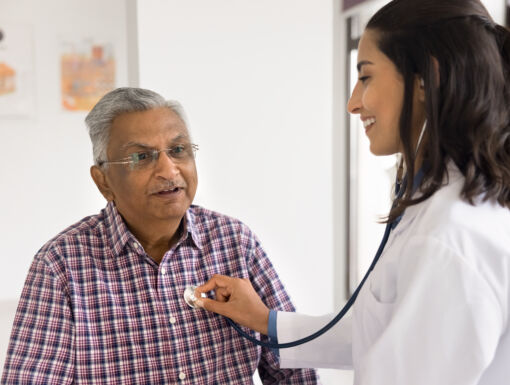 Female cardiologist holding stethoscope on older mans chest
